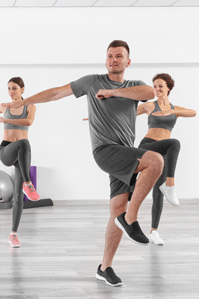 Ein Mann und zwei Frauen machen Pilates in einem Fitnessraum